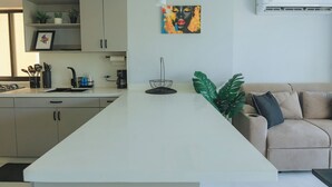 A modern kitchen with a central island, a dining area with a sofa, and a large plant. - Cartagena Gem, Fully Renovated Retreat Just Minutes from Playa Hollywood (Cartagena)