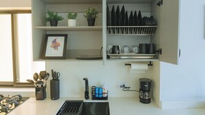 A kitchen with a sink, stove, and various utensils. There are potted plants on the shelves and a framed map on the wall. - Cartagena Gem, Fully Renovated Retreat Just Minutes from Playa Hollywood (Cartagena)