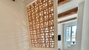A bedroom with a bed, a wooden partition, and a view of the outside.