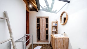 A bathroom with a wooden door, a sink, a mirror, and a towel on the floor.