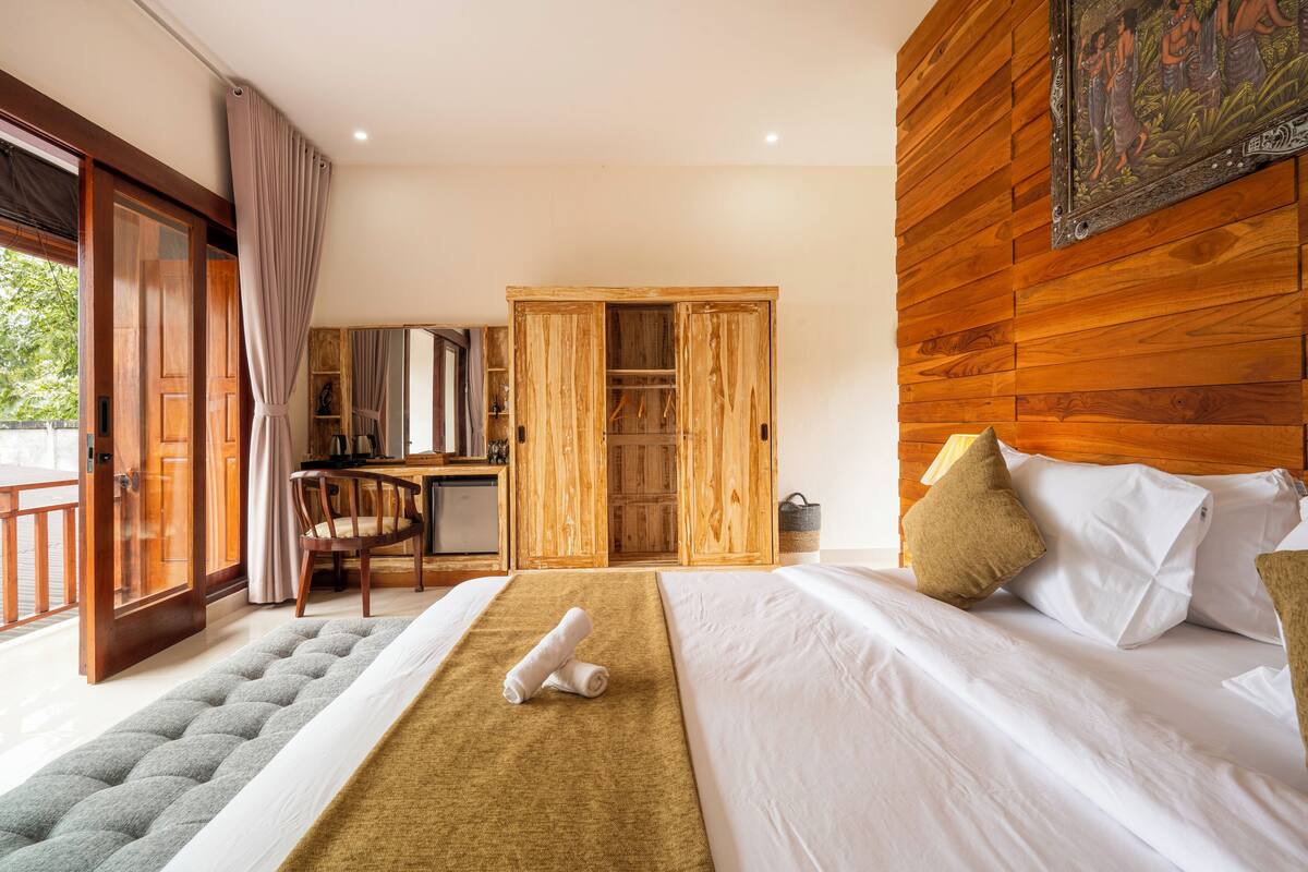 A bedroom with a bed, a desk, and a wardrobe.
