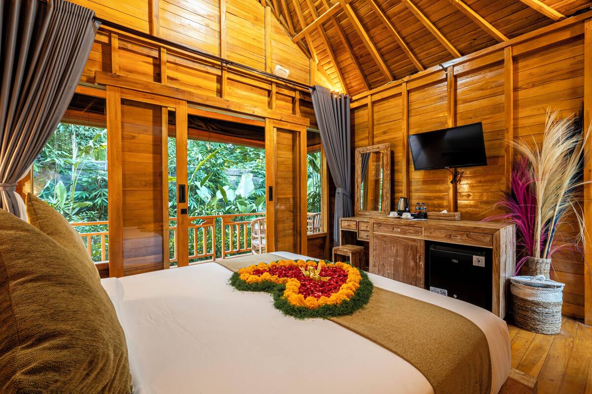 A wooden cabin with a bed, a desk, and a television.