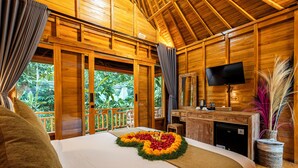 A wooden cabin with a bed, a desk, and a television.