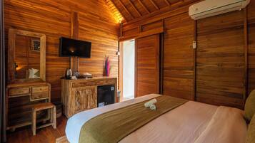 A wooden cabin room with a bed, a TV, a desk, and a wardrobe.