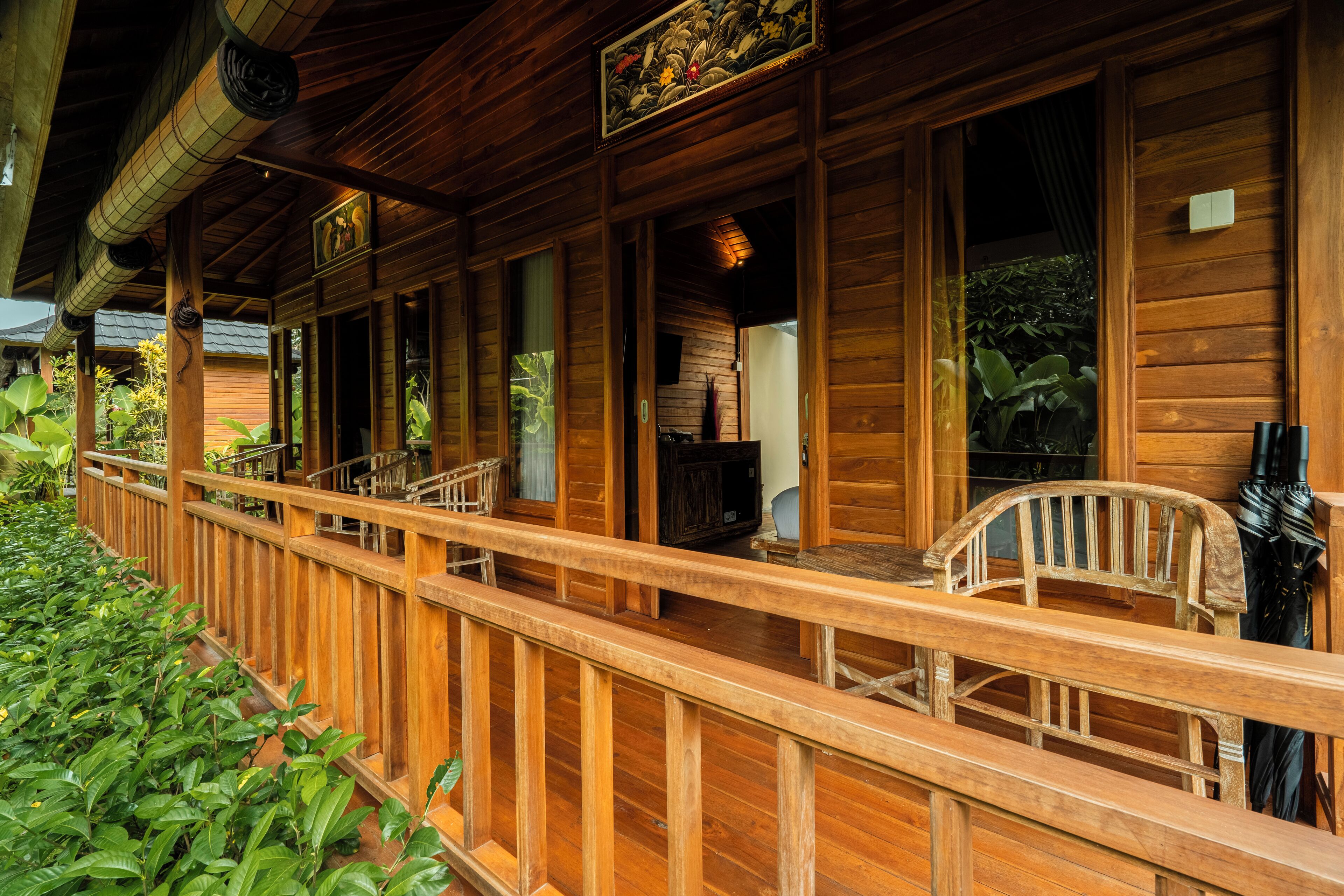 A wooden cabin with a porch, wooden railings, and a view of the surrounding greenery.