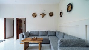 A living room with a grey sectional sofa, a wooden coffee table, and decorative wall art.