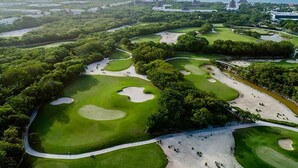 Eine Vogelperspektive eines Golfplatzes mit mehreren Grüns, Sandbunkern und einem umliegenden Waldgebiet.
