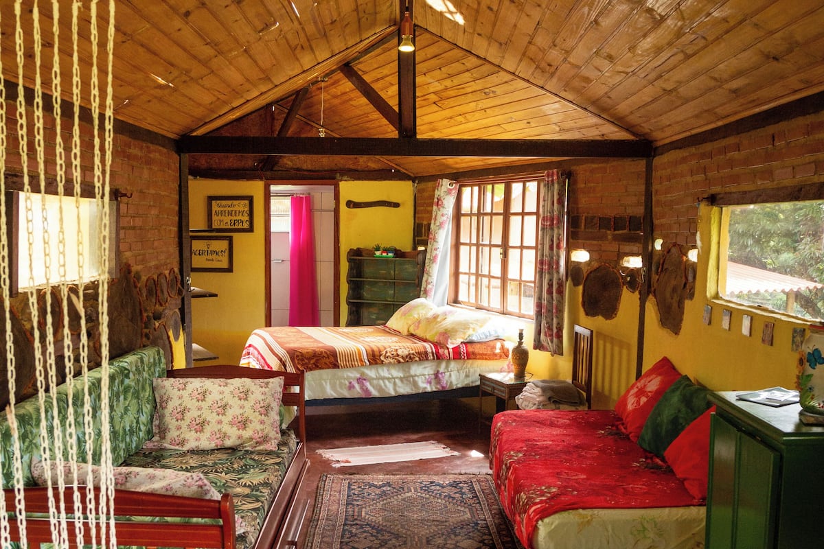 A cozy cabin with two beds, a wooden ceiling, a large rug, and a rustic decor.