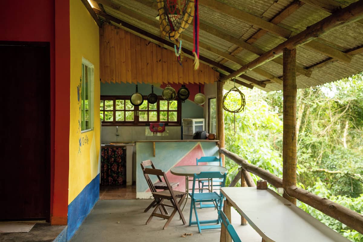 A rustic dining area with wooden furniture and a view of lush greenery.