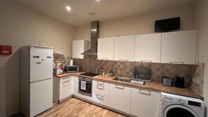A compact kitchen with a refrigerator, microwave, oven, sink, and washing machine. - Market Street Aberdeen Apartment (Aberdeen)