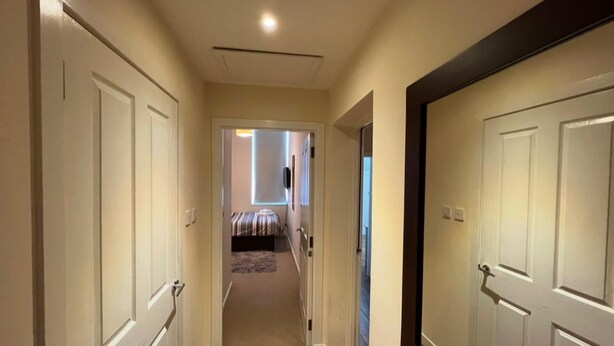 A hallway with wooden flooring leading to a bedroom with a bed and a window. - Market Street Aberdeen Apartment (Aberdeen)