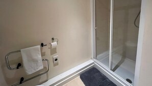 A bathroom with a shower, a towel rack with a towel, and a toilet paper holder. - Market Street Aberdeen Apartment (Aberdeen)