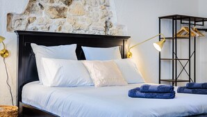 Una cama con sábanas blancas, cabecera negra y dos lámparas de noche.