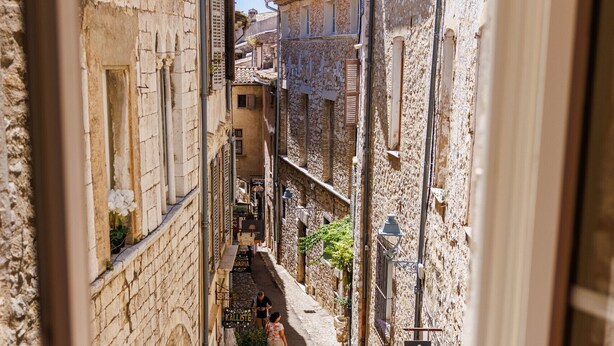 Una calle estrecha con edificios de piedra, un cartel que dice 'LE MAIRIE' y un estrecho sendero peatonal.