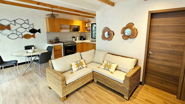 A modern kitchen with wooden cabinets, a dining table, and a sofa.