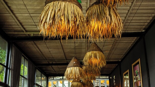 A room with a brick floor, wooden furniture, and thatched ceiling lamps. - Krazy Gecko Resort (Pokhara)