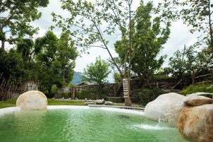 Una piscina natural rodeada de rocas y árboles.