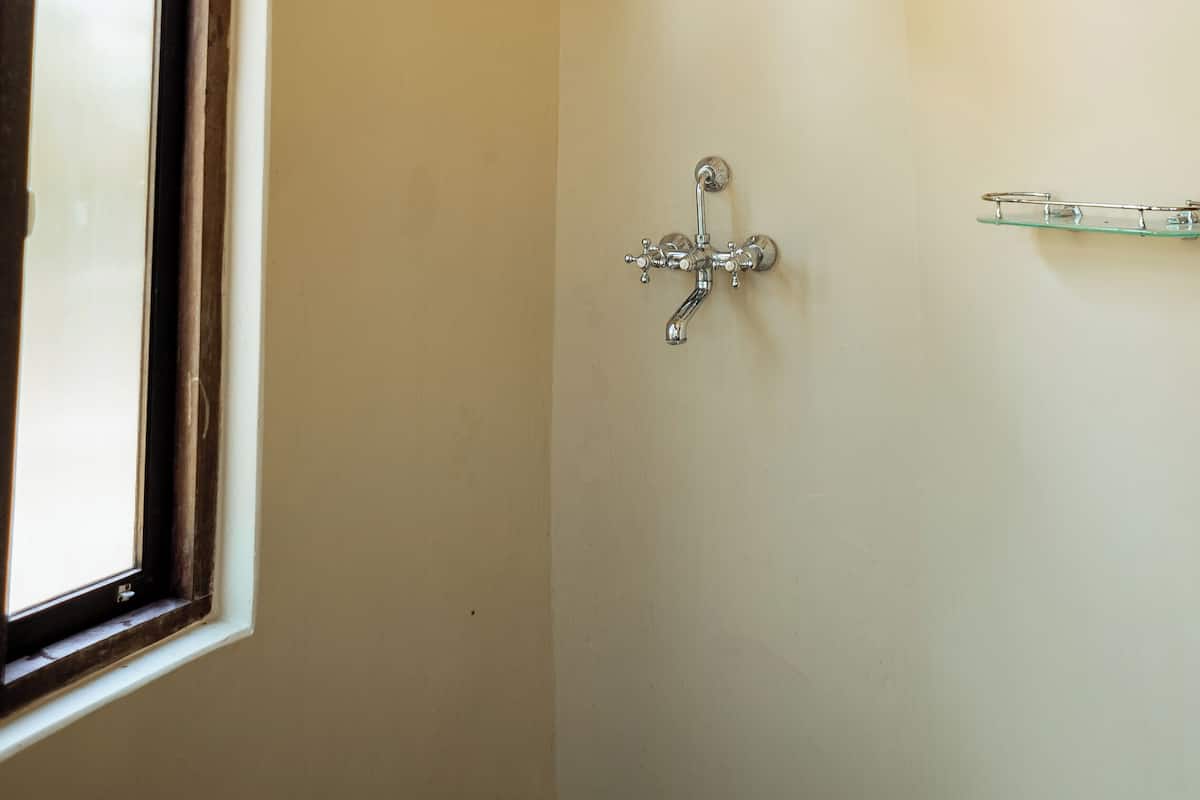A bathroom with a shower, a window, and a shelf.