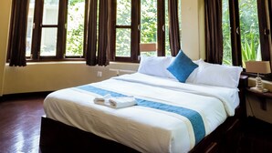 A hotel room with a large bed, multiple hanging lamps, and windows with curtains. - Krazy Gecko Resort (Pokhara)