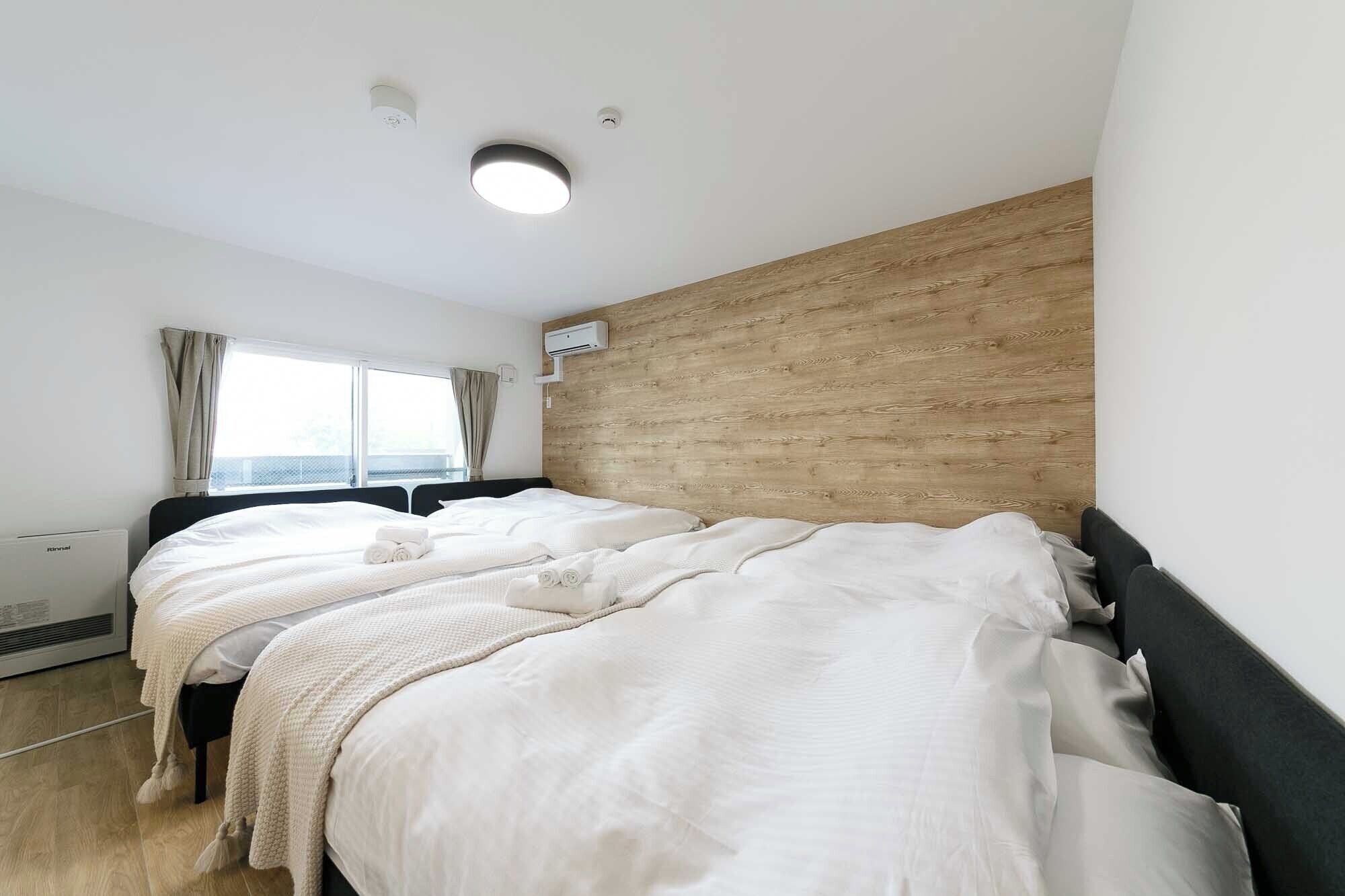 Una camera d'albergo con un grande letto, una finestra con tende, una parete decorata in legno e un condizionatore d'aria.