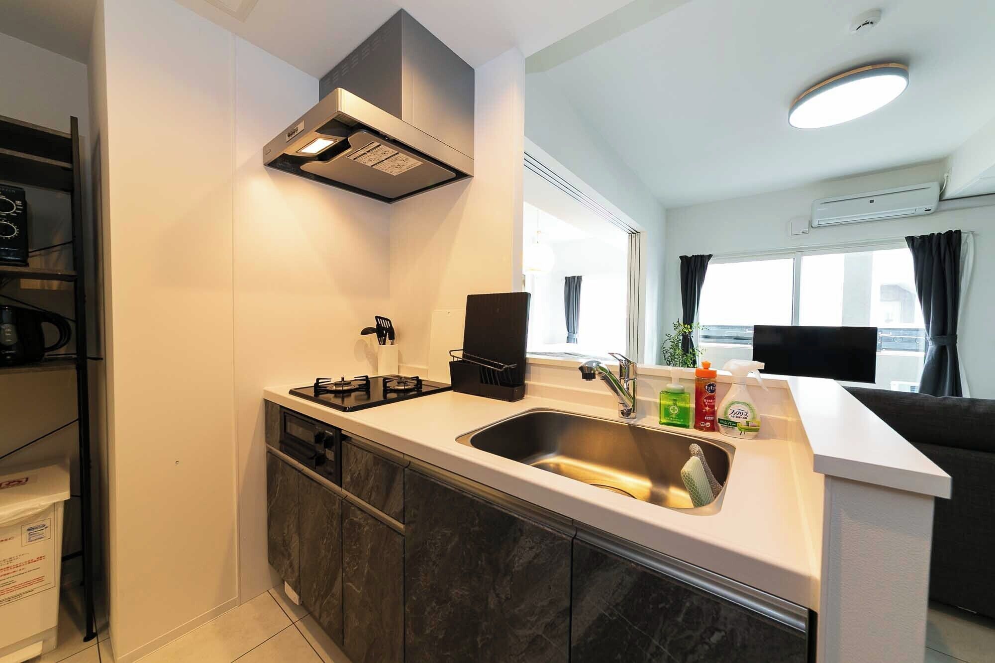 A compact kitchen with a gas stove, a sink, and a built-in oven. There is a window providing natural light and a view of the outside.