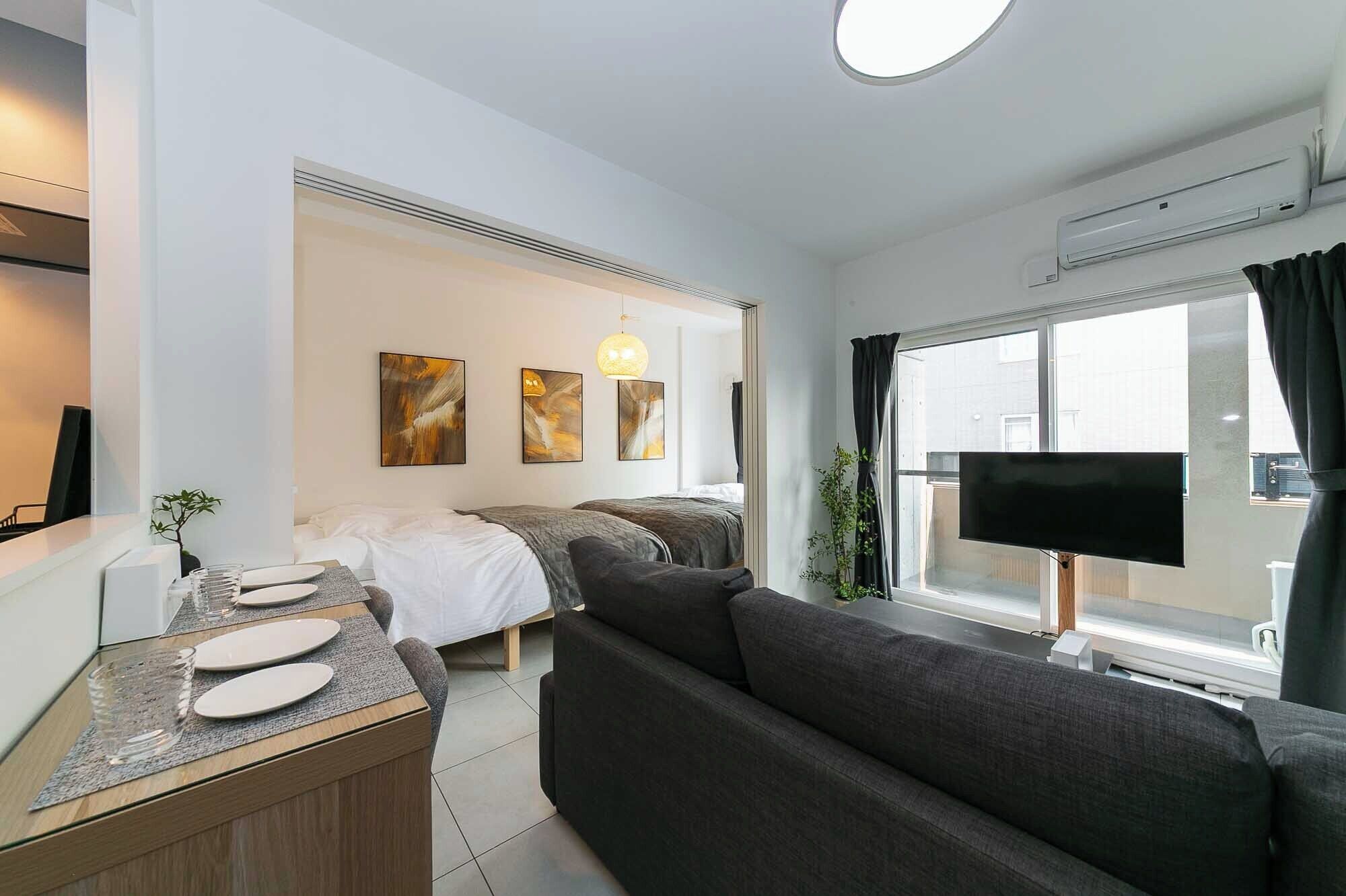 Una habitación de hotel moderna con cama, sofá, televisor y zona de comedor.