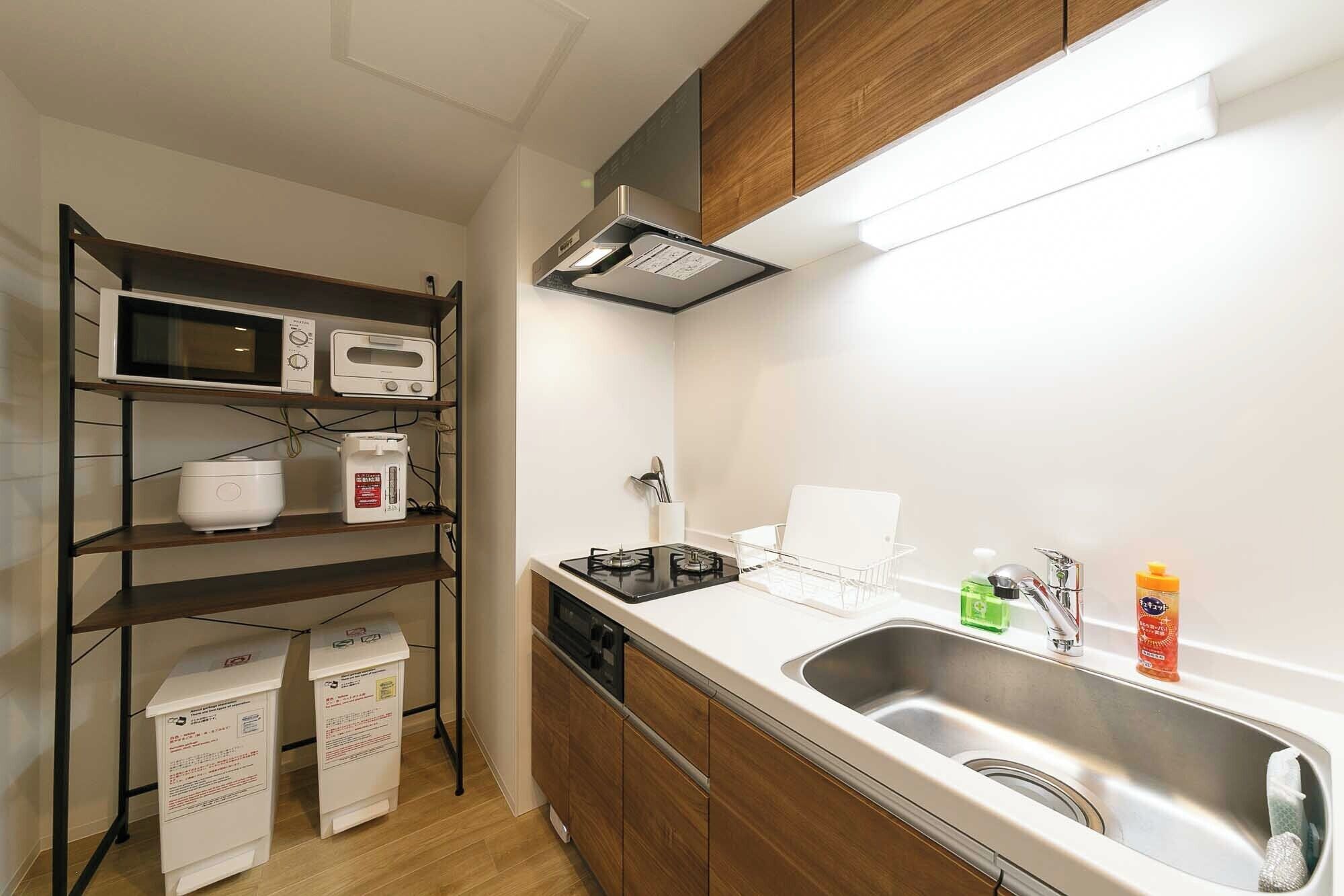 Une cuisine compacte équipée d’un four à micro-ondes, d’un grille-pain et d’une cuisinière. On y trouve des placards, un évier et un petit plan de travail.