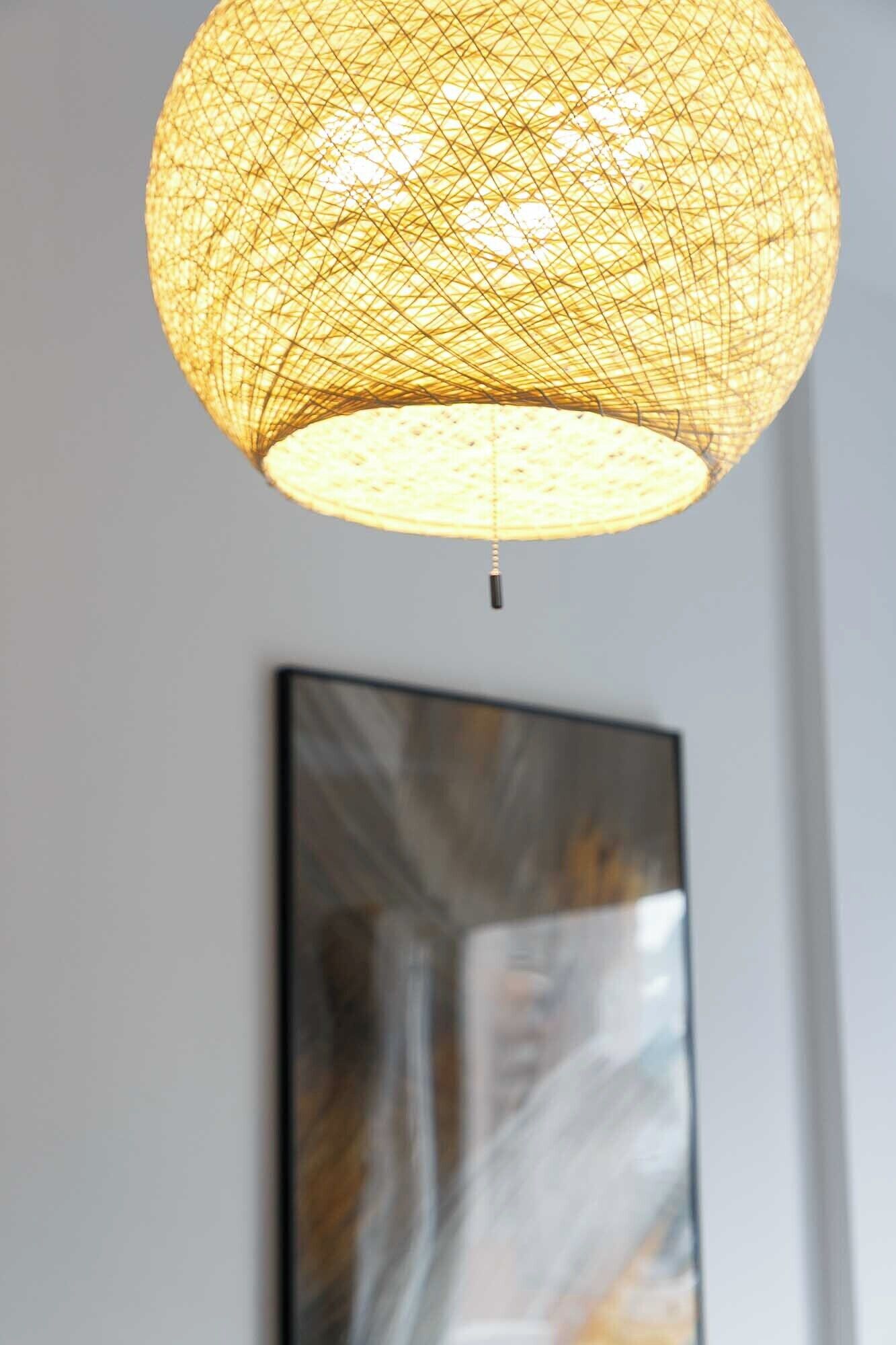 A spherical, woven pendant light fixture with a visible cord hanging from the bottom.