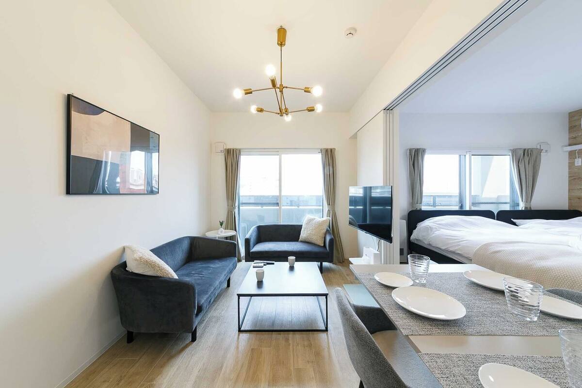 A modern hotel room with a large bed, two sofas, a coffee table, and a TV.