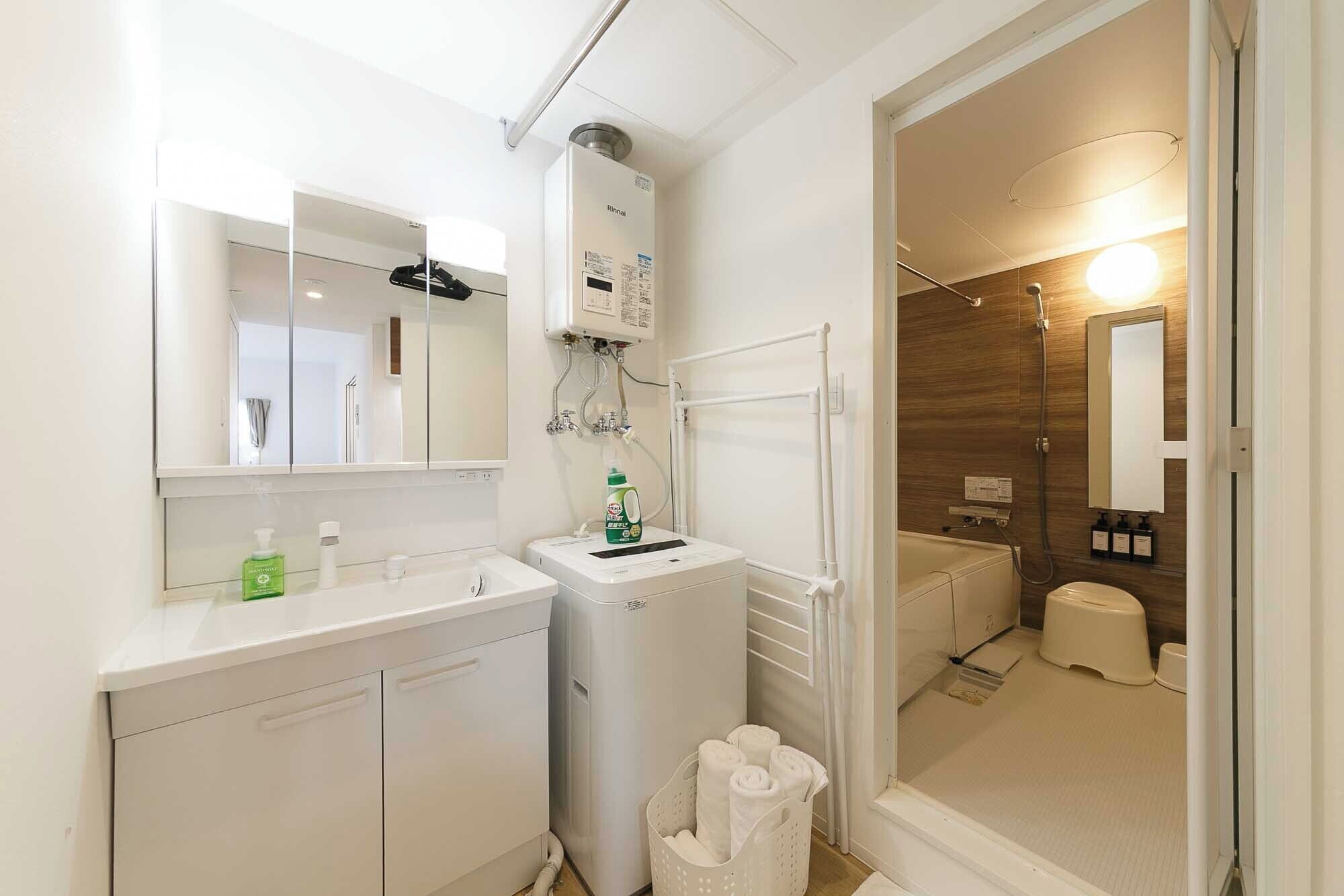 Une salle de bain moderne équipée d’un lavabo, d’un miroir, d’un porte-serviettes et d’un espace douche.