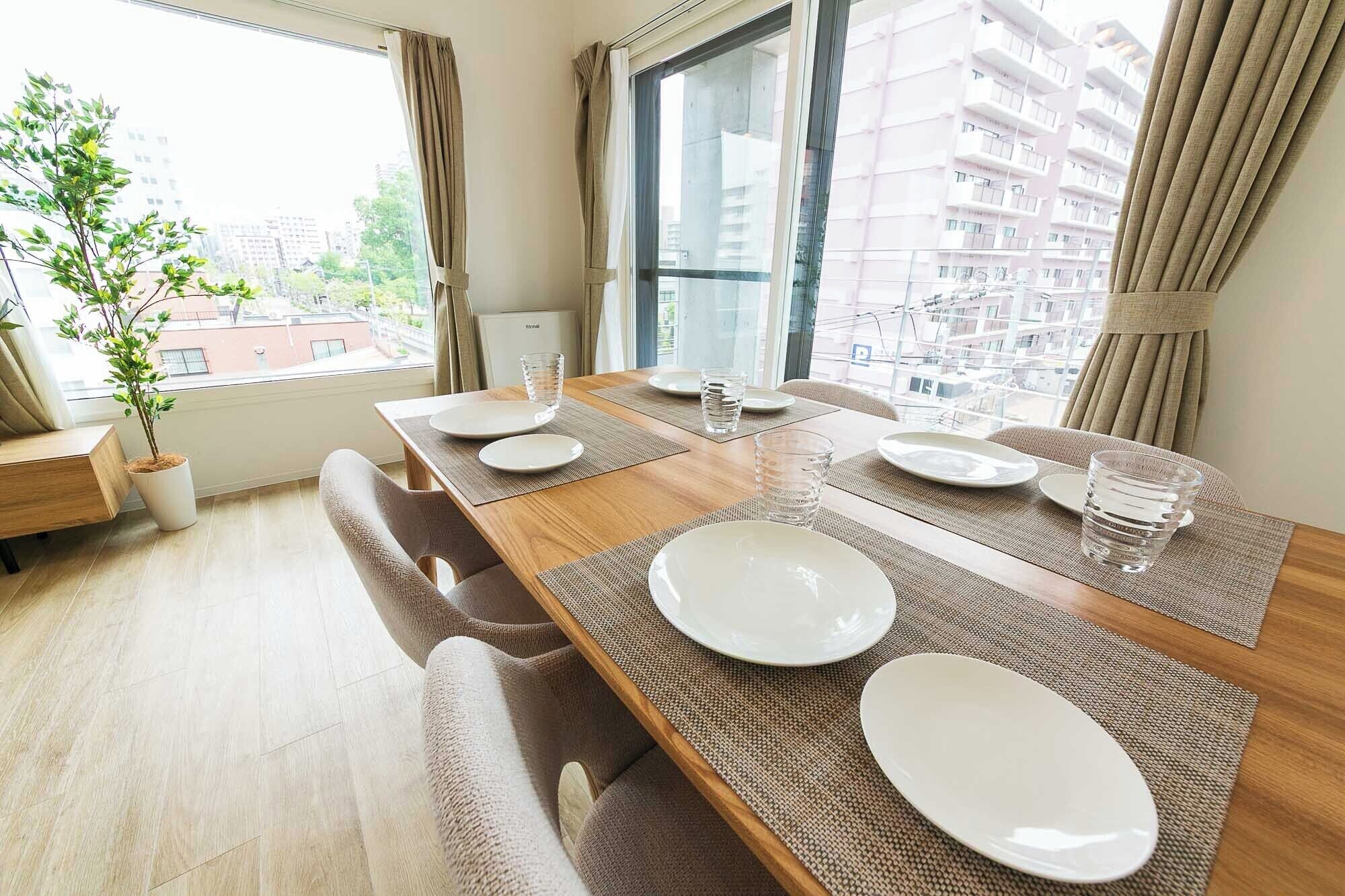 A dining area with a wooden table set for four, surrounded by cushioned chairs.