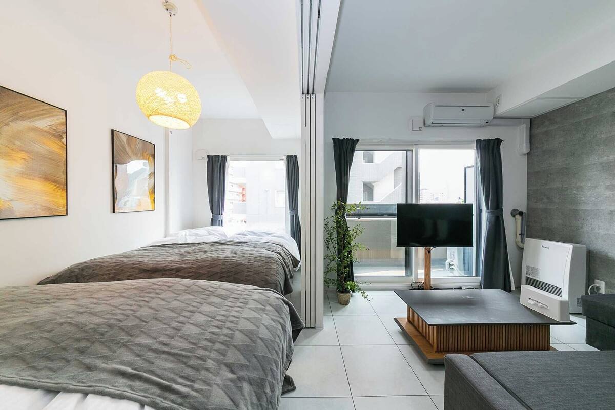 A modern bedroom with two beds, a TV, and a small seating area.