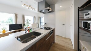 A modern kitchen with a large island, built-in oven, and a flat-screen TV. - EFFECT minami7 (Sapporo)