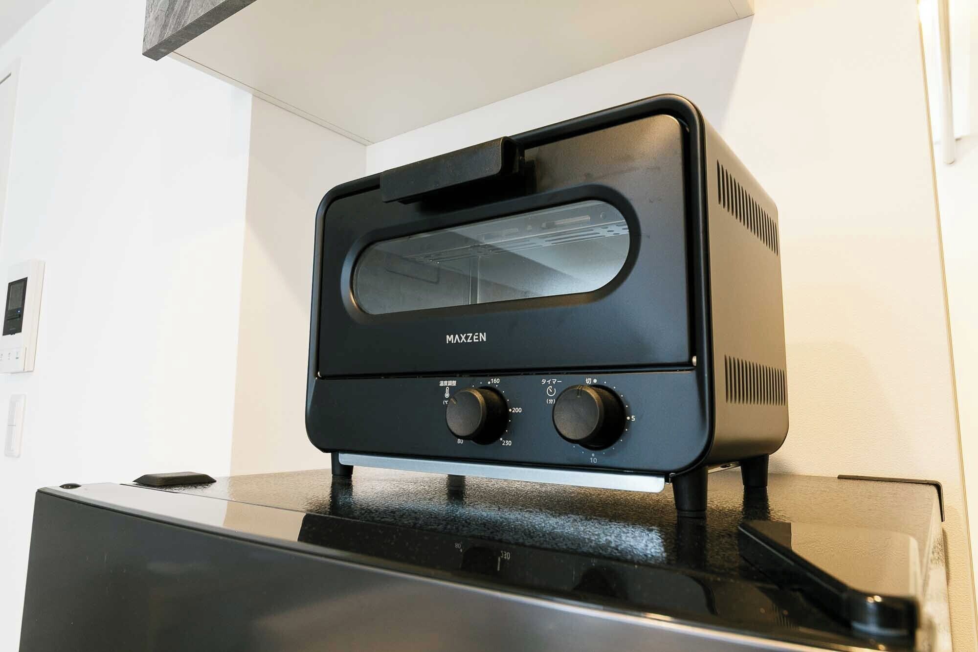 Un horno tostador MAXZEN negro con tres perillas de control sobre una encimera negra.