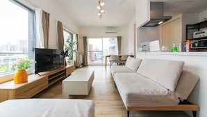 A modern living room with a sofa, TV, and a dining area. - EFFECT minami7 (Sapporo)