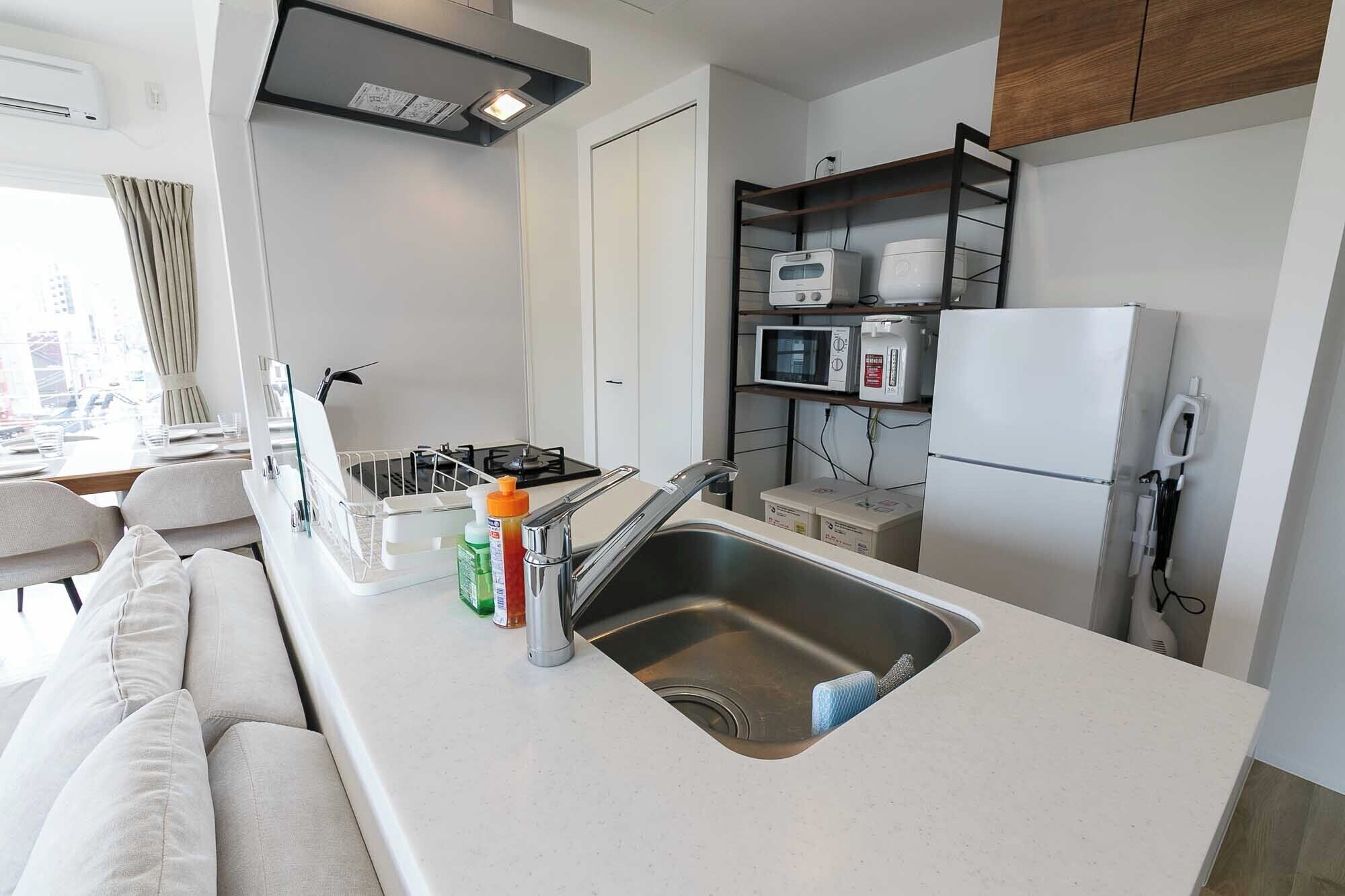 A modern kitchen with a stainless steel sink, a gas stove, and built-in appliances including a microwave and refrigerator.