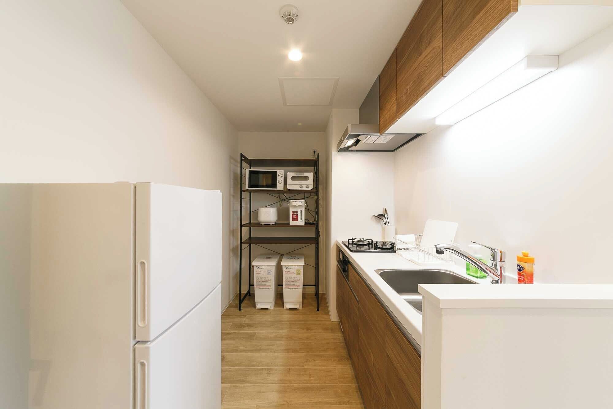 A compact kitchen with a refrigerator, microwave, and gas stove.