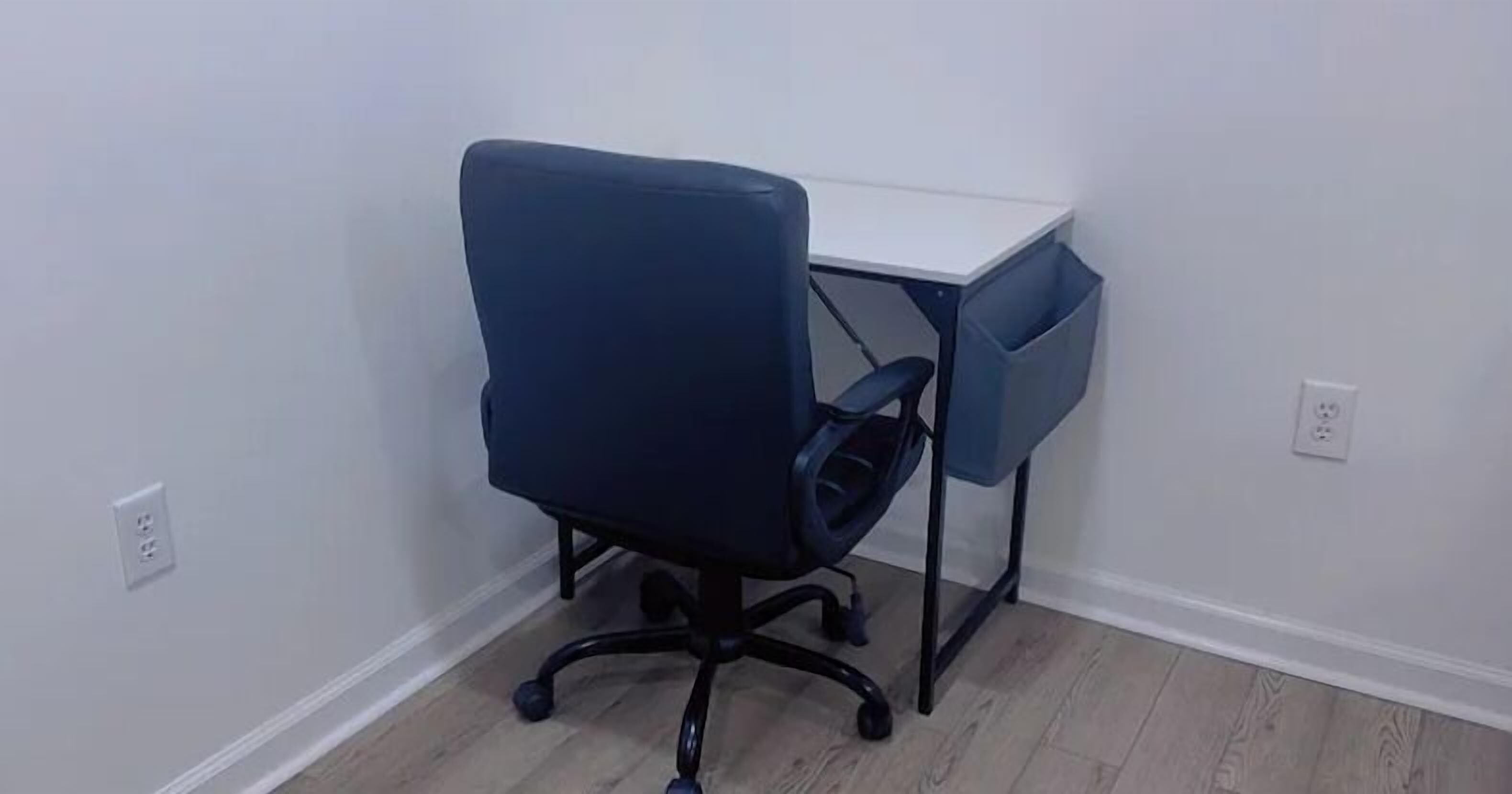 Ein kleiner Büroraum mit einem Schreibtisch und einem blauen Bürostuhl.