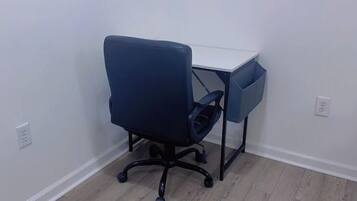Ein kleiner Büroraum mit einem Schreibtisch und einem blauen Bürostuhl.