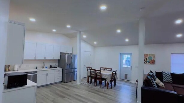 A modern kitchen with white cabinets, a stainless steel refrigerator, and a dining area with a table and chairs. - Quiet 2BR-Retreat Near Alum Creek & Lewis Center (Delaware)