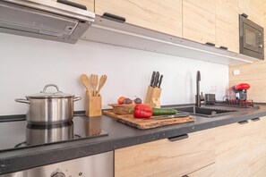 Een moderne keuken met een roestvrijstalen pan, houten keukengerei, een snijplank met groenten en een messenblok.