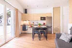 Una cocina moderna con armarios de madera, horno empotrado y comedor con mesa y sillas.