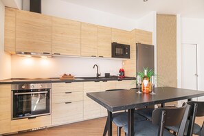 A modern kitchen with wooden cabinets, a built-in oven, a microwave, and a refrigerator. There is a dining table with chairs and a bottle of wine. - Calahonda Beach A, Mijas Costa, Spain (Mijas Costa)