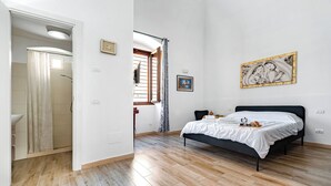 Una camera da letto con un letto, una finestra e un bagno visibile attraverso una porta aperta.