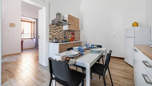 Una cucina compatta con angolo ristoro, pavimento in legno e vista su un balcone.