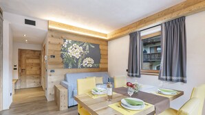 A dining area with a wooden table set for two, a sofa, and a painting on the wall. - Livia, Livigno, Italy (Livigno)