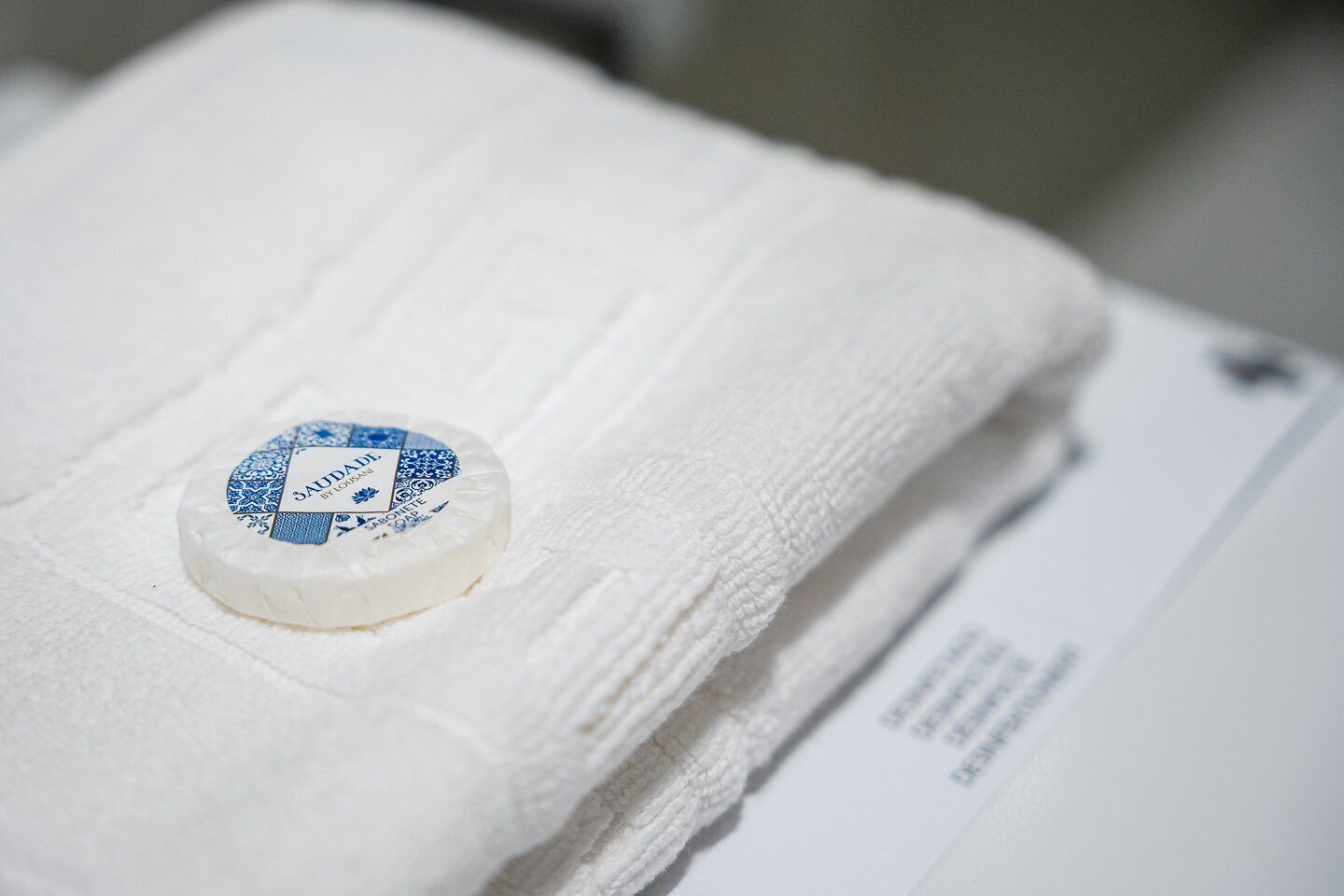 A white towel with a blue and white label on it, placed on a white surface.