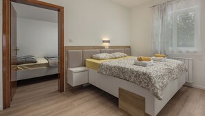 A modern bedroom with a bed, bedside table, and a window with curtains. - Sea and Silence Apt /w Sea View Balcony, Lopar, Croatia (Lopar)