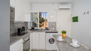 A compact kitchen with a washing machine, a coffee station, and a view of the outside. - El Faro Hideaway by Lica Homes (Mijas)