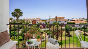 A balcony with a view of a coastal town, a table with a glass of wine, and a chair with a towel. - El Faro Hideaway by Lica Homes (Mijas)